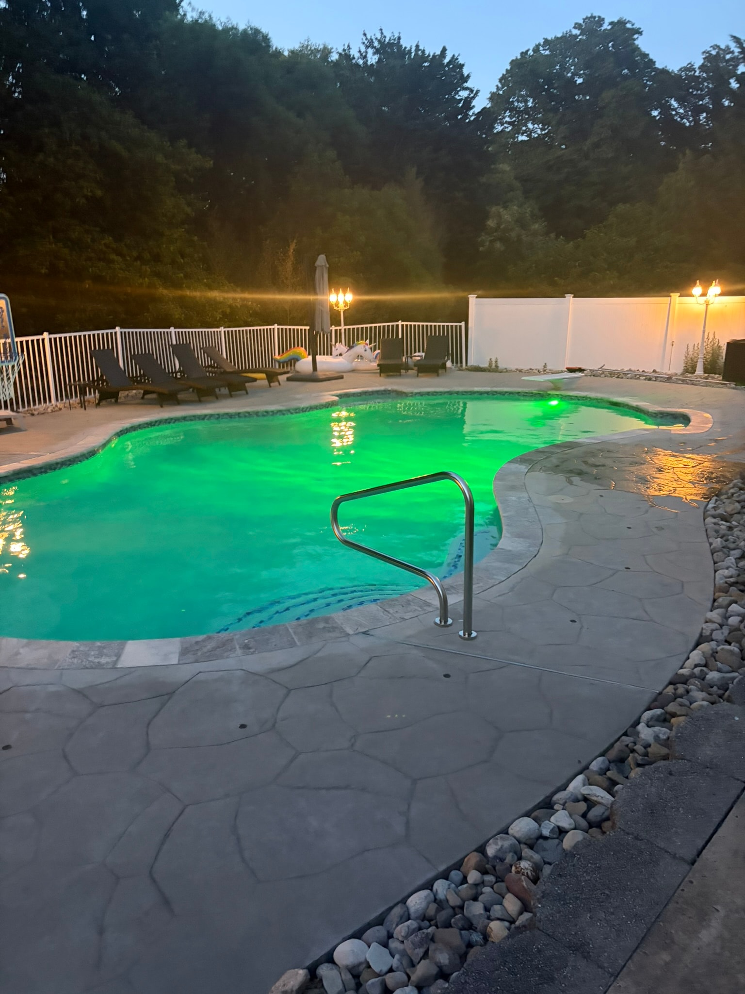Spa Electrics LED pool light — emerald green at dusk, flagstone deck